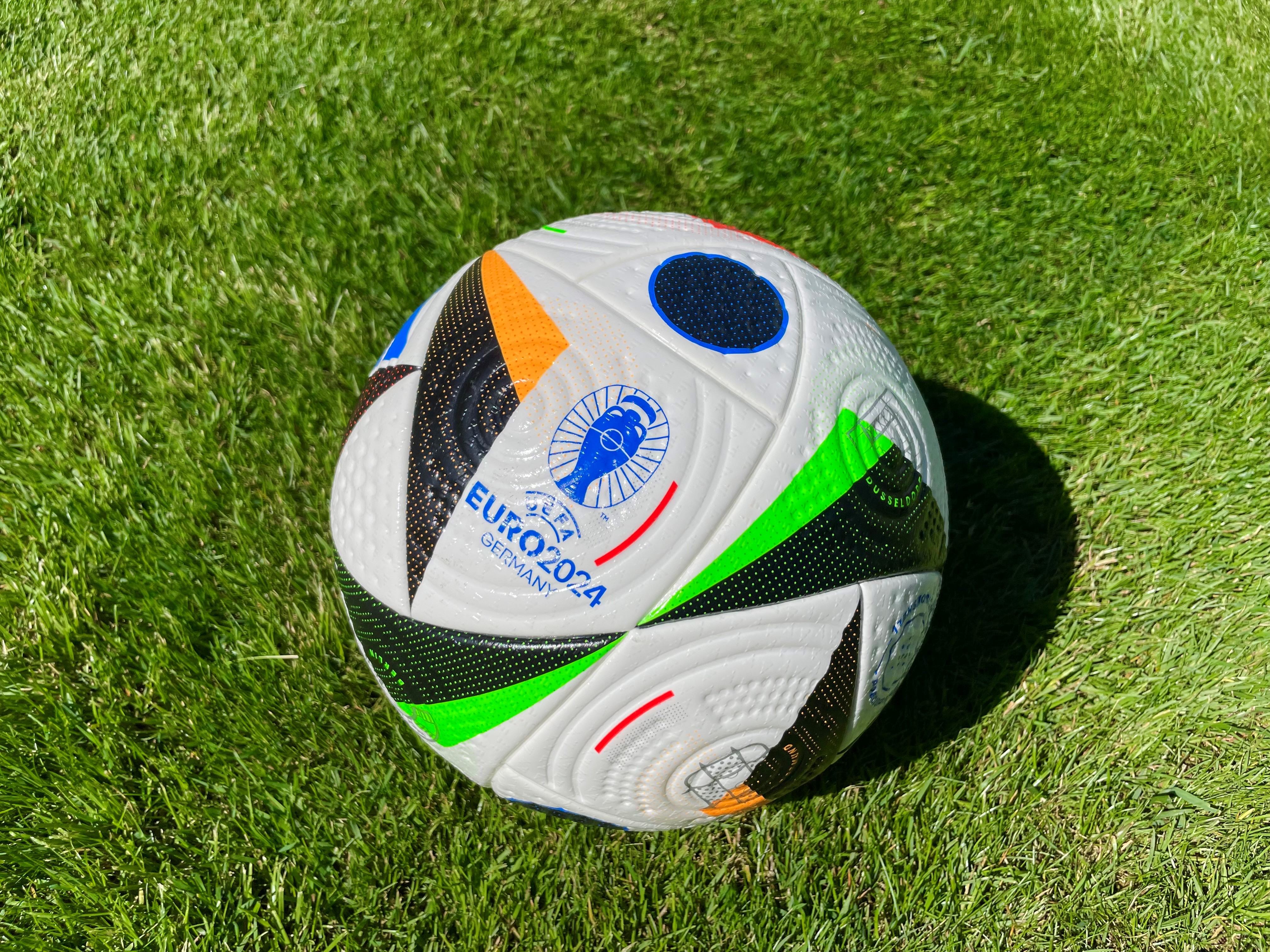 An image of an Adidas Fussballliebe ball on a freshly mowed lawn.